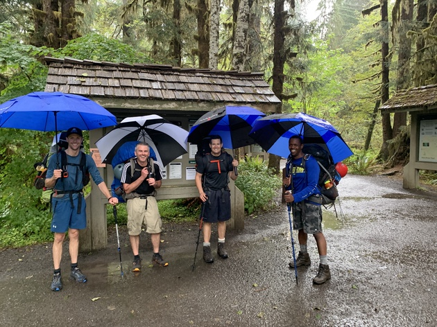 Team with golf umbrellas hiking to Mt. Olympus high camp