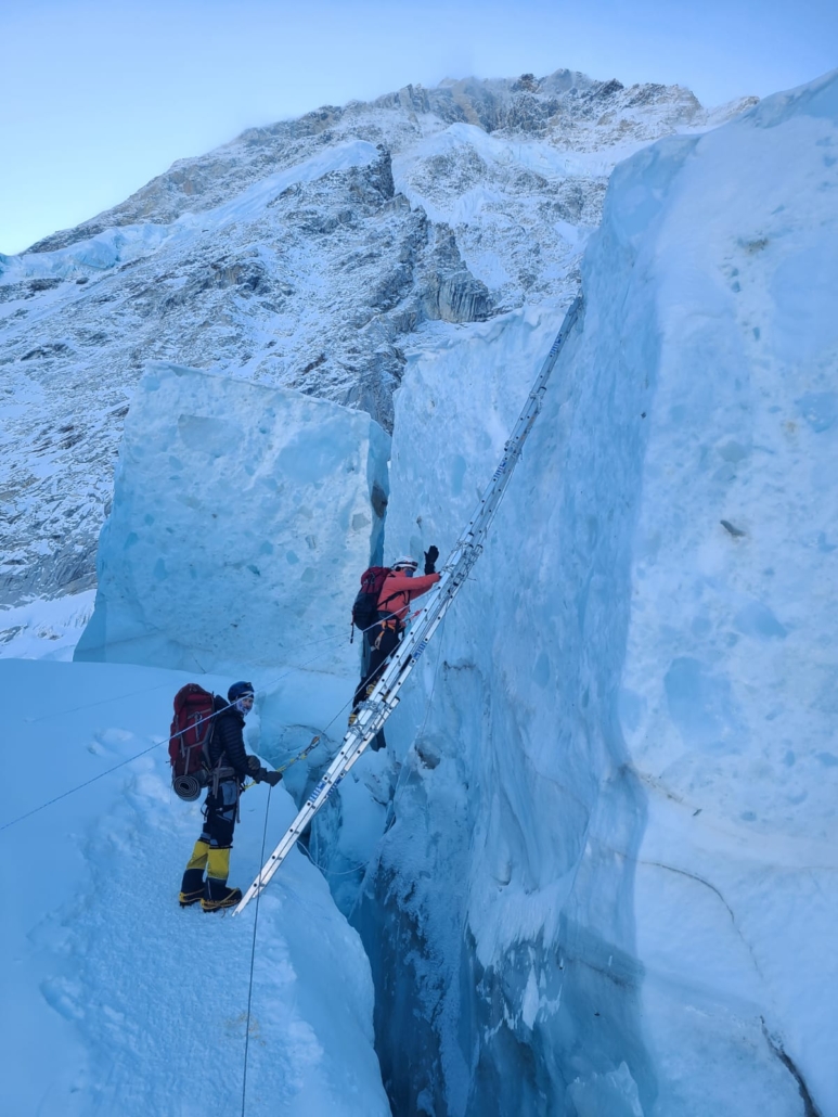 Climbers ascending one of the many ladders that connect sections of the broken Khumbu Icefall.