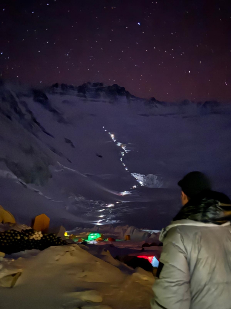Headlamps line the Lhotse Face under a clear night sky.